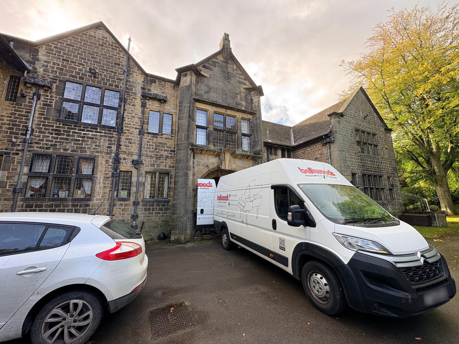 Bellwoods Removals van backed up to the arched stone entrance of Banney Royd Hall in Edgerton, Huddersfield, delivering a Yamaha grand piano