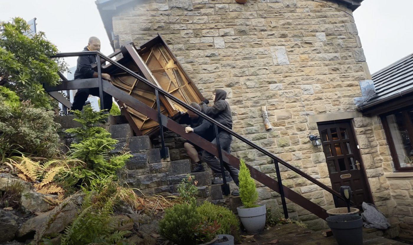 Bellwoods crew moving a piano down steps for disposal