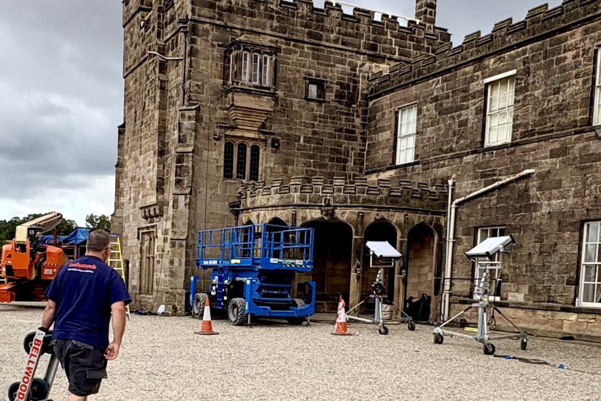 A Bellwoods crew member carrying a piano skate across the courtyard at Ripley Castle during a film shoot