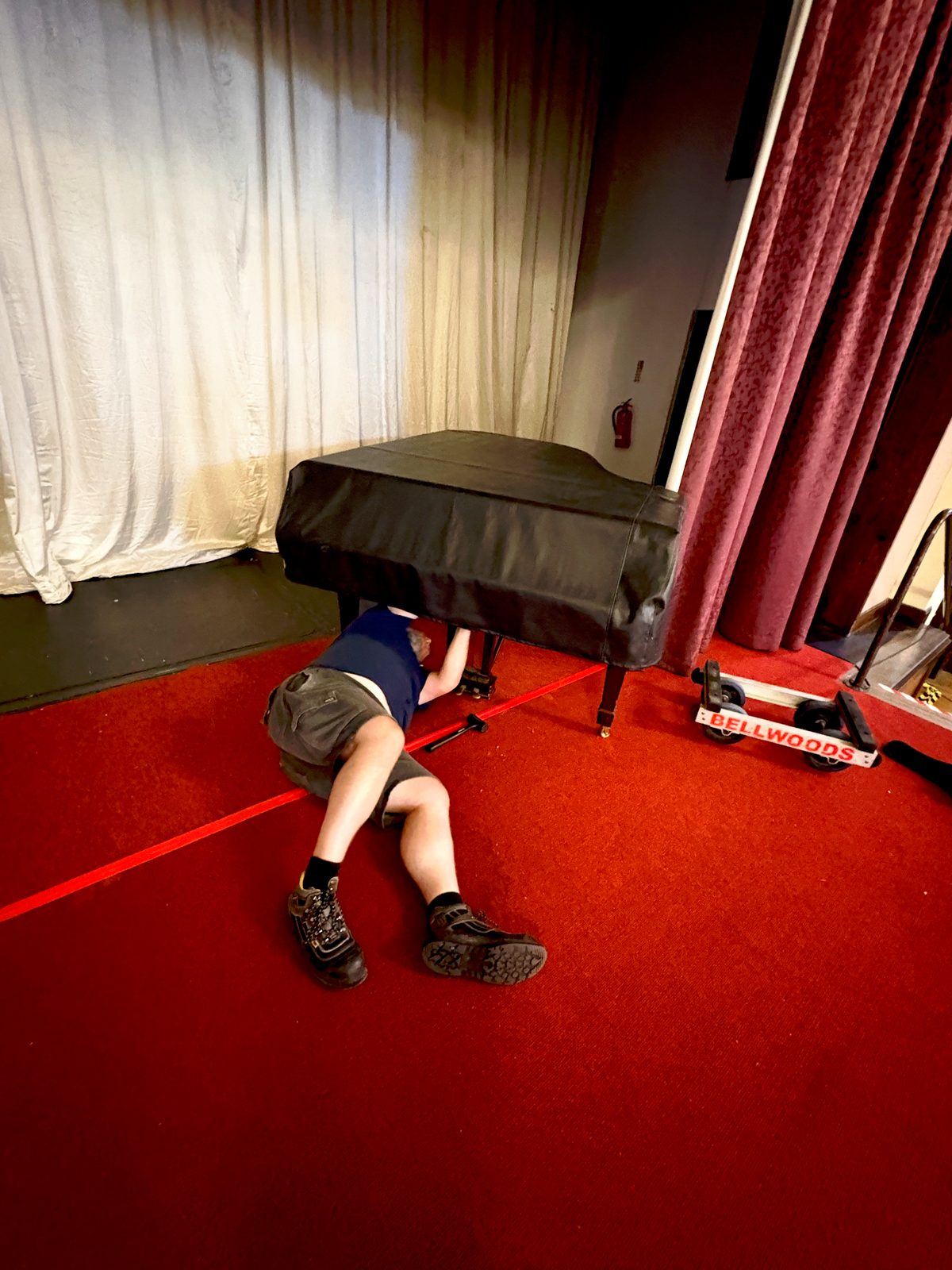 Bellwoods piano mover refitting the pedal lyre to a Steinway grand piano on the Civic Hall stage at Wallasey Town Hall